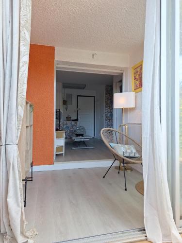 - un salon avec une chaise et un mur orange dans l'établissement Mimilou Eleuthera 500 metres du centre naturiste, au Cap d'Agde