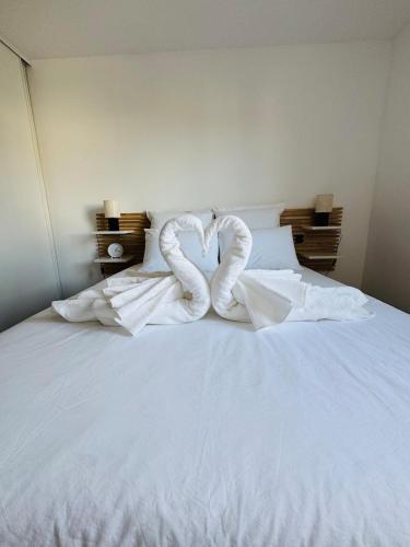 a white bed with two swans forming a heart at Appartement T2 Sérénité Lumineux et Tranquille in Saint-Alban