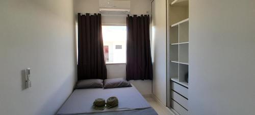 a small room with a bed with shoes in it at Mar Calmo, 150m da praia in Santa Cruz Cabrália