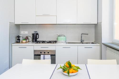 a kitchen with white cabinets and a bowl of fruit on a table at Luxury Seaview Apartments Manarola by Arbaspàa in Manarola