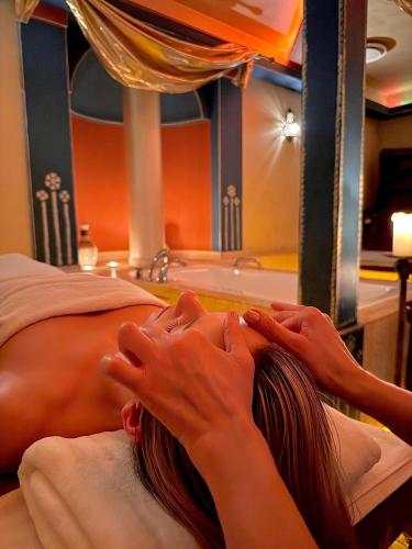 a woman laying on a bed in front of a sink at Papuga Park Hotel Wellness Marrakesz & SPA in Bielsko-Biala