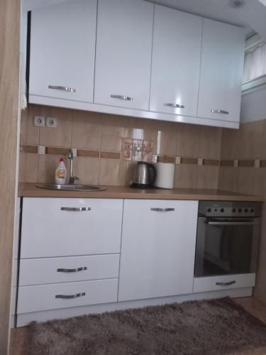 a white kitchen with white cabinets and a sink at Apartman Rada 2 in Bijeljina