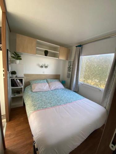 une chambre avec un grand lit avec une fenêtre dans l'établissement Mobilhom 143, à Sainte-Marie-du-Mont