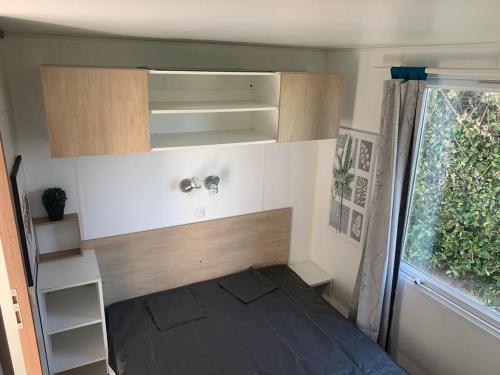 une petite pièce avec un lit et une fenêtre dans l'établissement Mobilhom 143, à Sainte-Marie-du-Mont