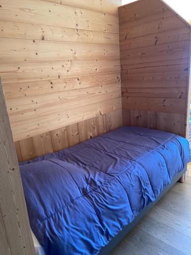 a bed in a room with a wooden wall at Chalet Fleur des Alpes 2 in Les Gets