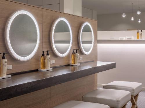 a bathroom with three mirrors and bottles on a counter at Mitsui Garden Hotel Nagoya Premier in Nagoya