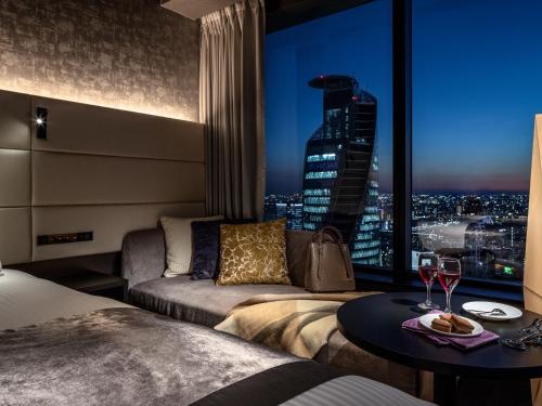a hotel room with a bed and a table with wine glasses at Mitsui Garden Hotel Nagoya Premier in Nagoya