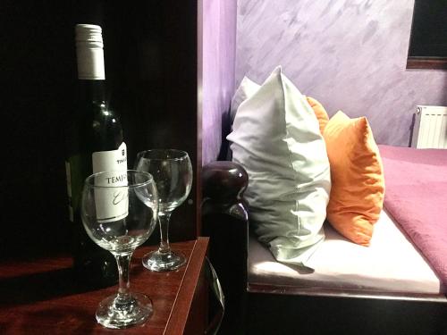 Una botella de vino y dos copas en una mesa en Smestaj Grof Mrcajevci, en Gusta Međa