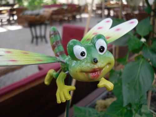 a small green dragonfly toy hanging from a plant at Hotel Den Helder in Den Helder