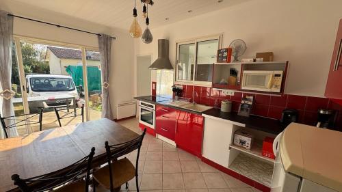 a kitchen with red cabinets and a table with a microwave at Maison in Chatuzange-le-Goubet
