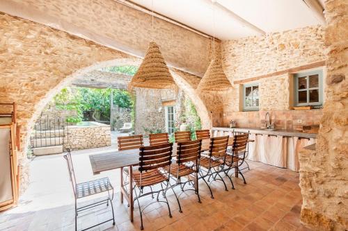 une cuisine avec une table et des chaises et un mur en pierre dans l'établissement Mas de 190m2 Climatisé avec Piscine et Cuisine d'été - 10 pers, à La Fare-les-Oliviers
