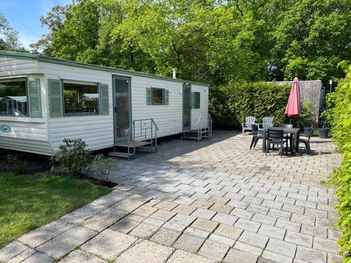 a white trailer with a patio with a table and chairs at Stacaravan op Camping de Haer Aan de rand van Ootmarsum in Klein-Agelo