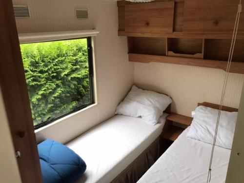 una piccola stanza con due letti e una finestra di Stacaravan op Camping de Haer Aan de rand van Ootmarsum a Klein-Agelo