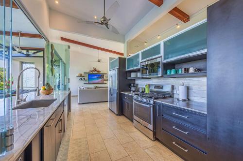 a large kitchen with blue cabinets and stainless steel appliances at Ocean View Villa With Pool and Spectacular Sunsets in Ballena