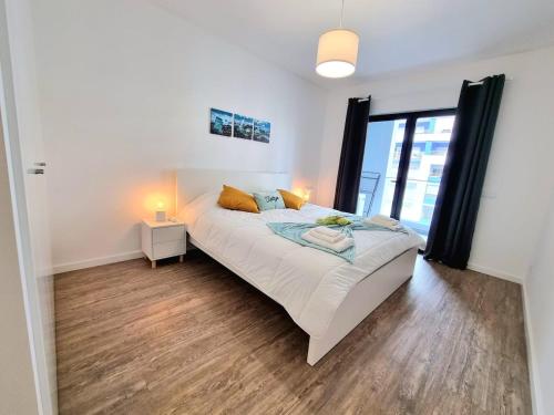a white bedroom with a bed and a window at Modern Apartment in Portimão in Portimão