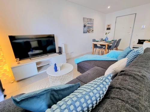 a living room with a couch and a flat screen tv at Modern Apartment in Portimão in Portimão