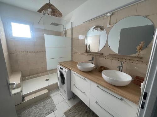 une salle de bain avec deux lavabos et une machine à laver dans l'établissement Joli appartement vue Pyrénées, à Pau