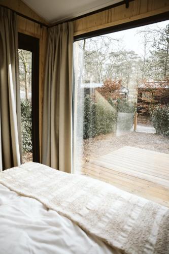 a bedroom with a bed and a large window at Tinyhouse NaNo in Nunspeet