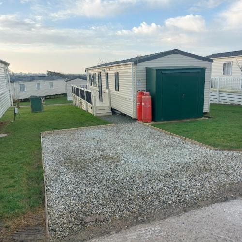 a house with a green garage and a gravel driveway at Bude Coastal Lodge in Bude