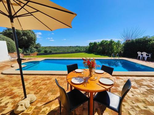 a table with chairs and an umbrella next to a pool at Villa Nuralux - Vistas Espectaculares, Piscina Privada y BBQ in Sant Climent