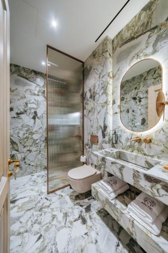 a marble bathroom with a toilet and a mirror at Arctic Boutique Hotel in Korçë