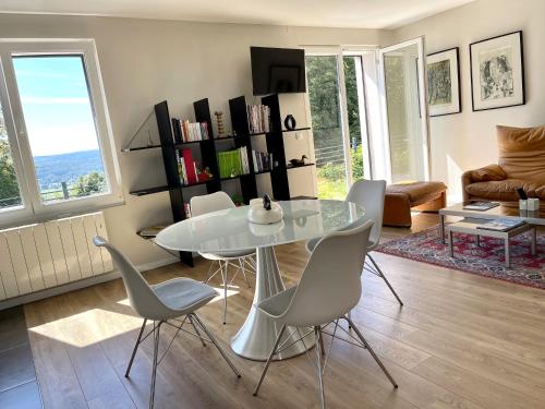 un salon avec une table et des chaises blanches dans l'établissement Maison cosy au-dessus du fort de Fontain vue magnifique sur les Montagnes du Jura, à Fontain
