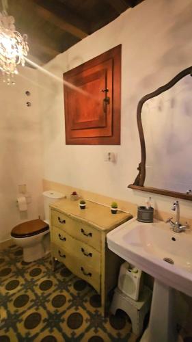 a bathroom with a sink and a toilet and a mirror at La Casa de Sofía in Navaconcejo