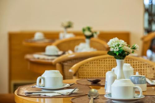 a table with white dishes and a vase of flowers at Minerva Premier Hotel in Thessaloniki
