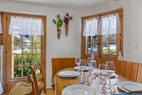 Un comedor con una mesa con copas de vino. en Chalet spacieux dans le Val Ferret, en Orsières