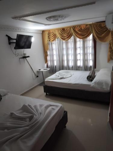 a bedroom with two beds and a tv and a window at Casa Emmalana in Santa Marta