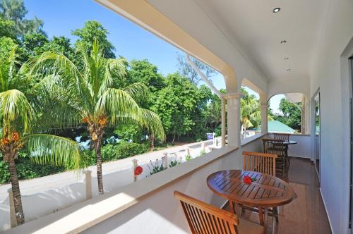 balcón con mesa, sillas y árboles en Yasad Residence, en Anse Possession