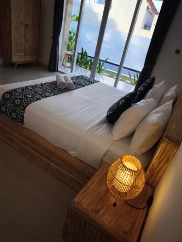 a bedroom with a large bed with a large window at Kubu Shankara Homestay in Uluwatu