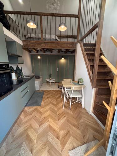 a kitchen and dining room with a wooden floor and stairs at Le refuge des Amoureux in Briord