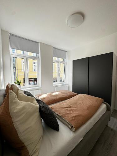 a bedroom with a large bed and two windows at Modernes Apartment am Marienplatz, Schwerin in Schwerin