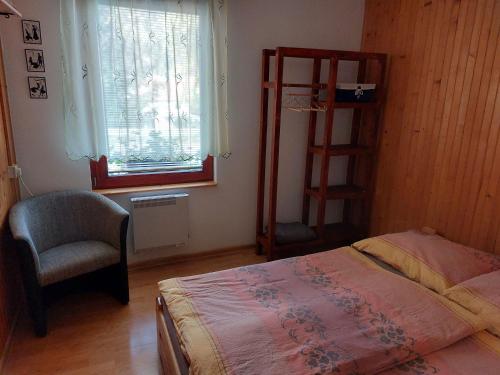a bedroom with a bed and a chair and a window at Chalupa na Hrbku in Belá