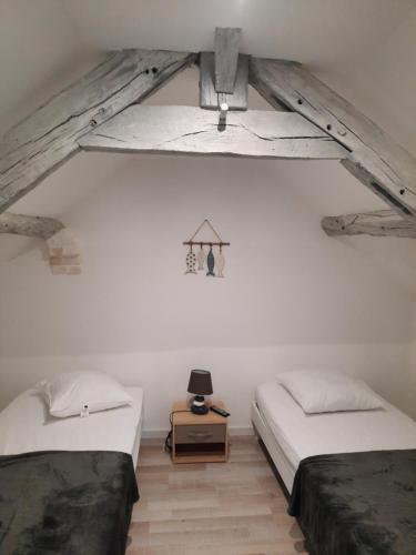 une chambre avec deux lits et une table dans une pièce dans l'établissement Le Bâbord, à Honfleur