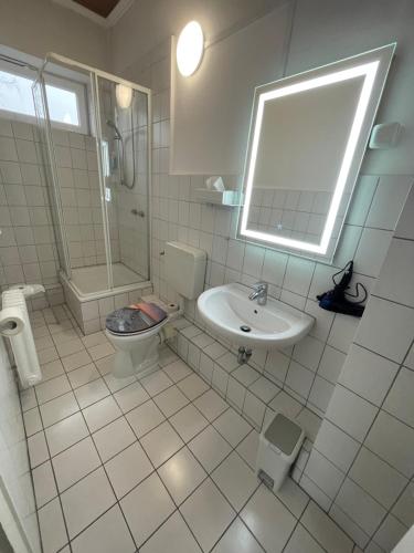 a bathroom with a sink and a toilet and a mirror at Schollers Restaurant & Hotel in Rendsburg