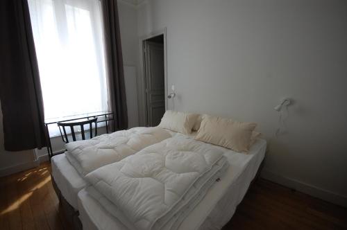 un grand lit blanc dans une chambre avec une fenêtre dans l'établissement 2 chambres St Germain des Prés, à Paris