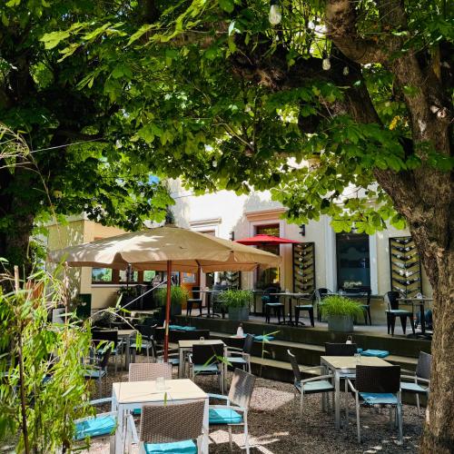 a restaurant with tables and chairs under a tree at Zum Rayers Café-Restaurant & Boutique-Hotel in Oberrotweil