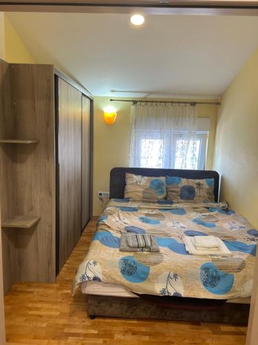 ein Schlafzimmer mit einem Bett mit einer blau-weißen Bettdecke in der Unterkunft Prestige 3 in Podgorica