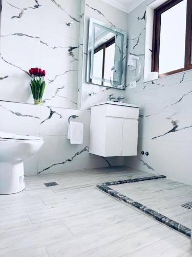 a white bathroom with a sink and a mirror at Kutal Park Inn Hotel in Përmet