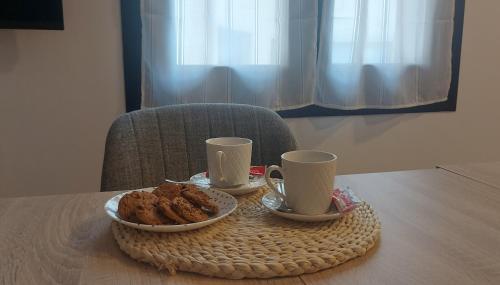 stół z dwoma kubkami i talerzem jedzenia w obiekcie Apartamento Sobrevilla SDR IV Sardinero w mieście Santander