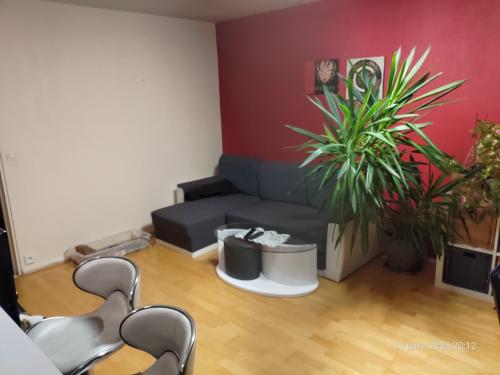 - un salon avec un canapé, des fauteuils et des plantes dans l'établissement Chambre à louer à saint-herblain, à Saint-Herblain