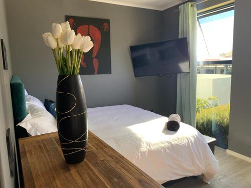 a black vase with white tulips in a bedroom at B&B Sitari County Estate - The Most Iconic Estate in Cape Town