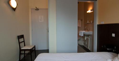 a bedroom with a white bed and a bathroom at Hotel De Londres in Lille