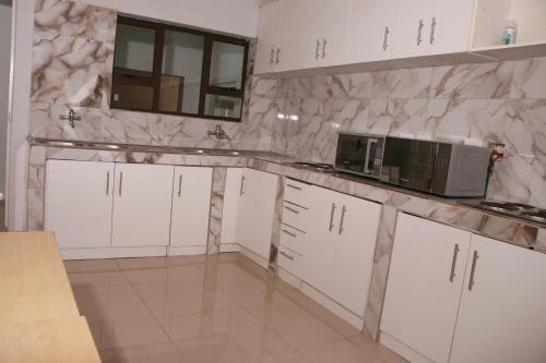 a kitchen with white cabinets and a microwave at Gift Guest house 3 in Cravenby