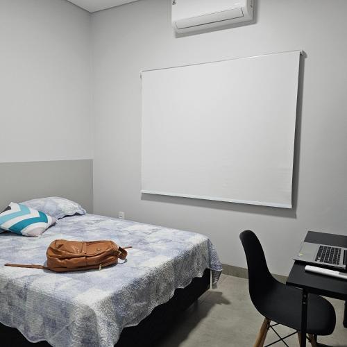 a purse sitting on a bed in a room with a laptop at Louvre Residence 202, conforto, estacionamento e wi-fi in Sinop