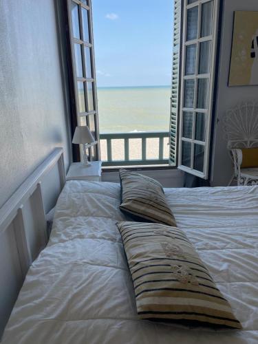 - un lit avec des oreillers dans une chambre avec une fenêtre dans l'établissement La Falaise, à Mers-les-Bains