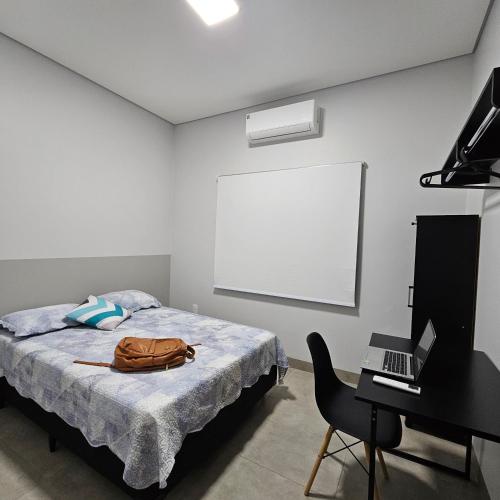 a bedroom with a bed and a laptop and a desk at Louvre Residence 202, conforto, estacionamento e wi-fi in Sinop