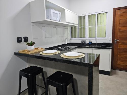 a kitchen with two stools at a counter with a microwave at Louvre Residence 202, conforto, estacionamento e wi-fi in Sinop